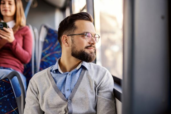 Porträt eines lächelnden Reisenden, der im Stadtbus neben dem Fenster